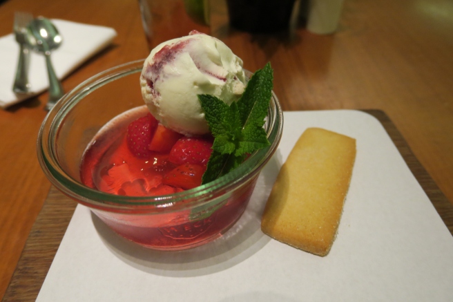 a bowl of red gelatin with ice cream and mint