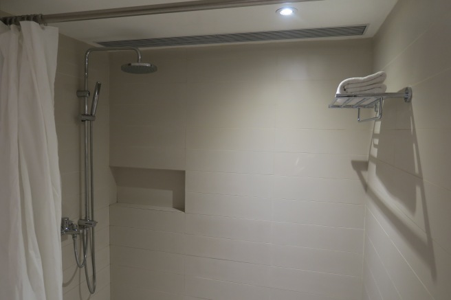 a shower with a towel rack and a shower head