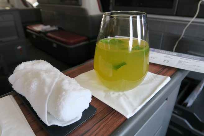 a glass of yellow liquid and a towel on a table