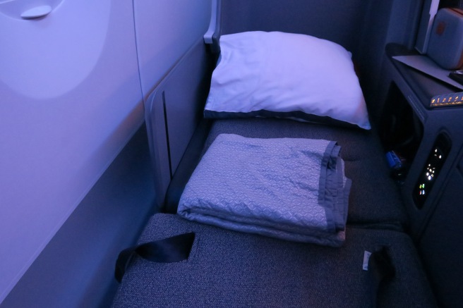 a bed with a pillow and a blanket on the back of a plane