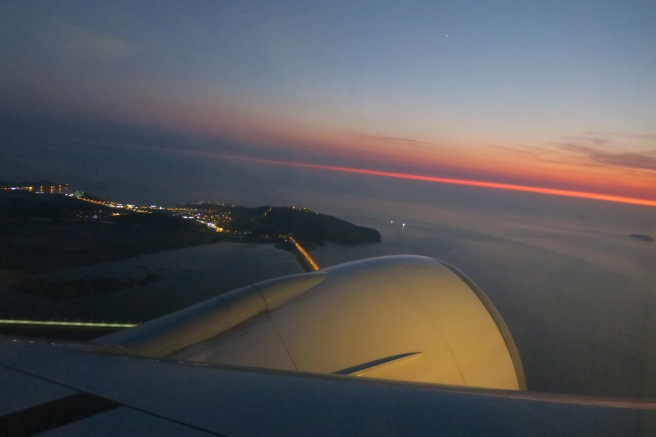 an airplane wing with a city in the distance
