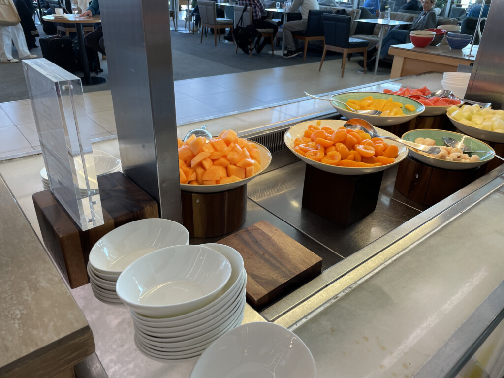 a buffet line with bowls of fruit
