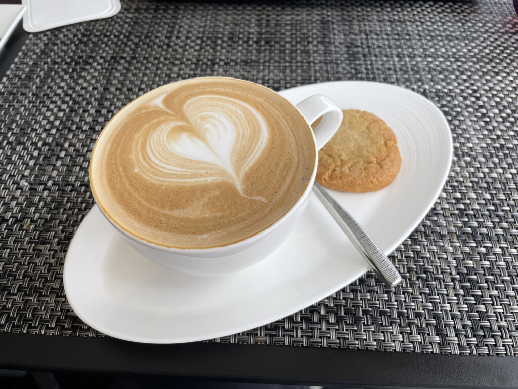 a cup of coffee with a heart design on top of a cookie