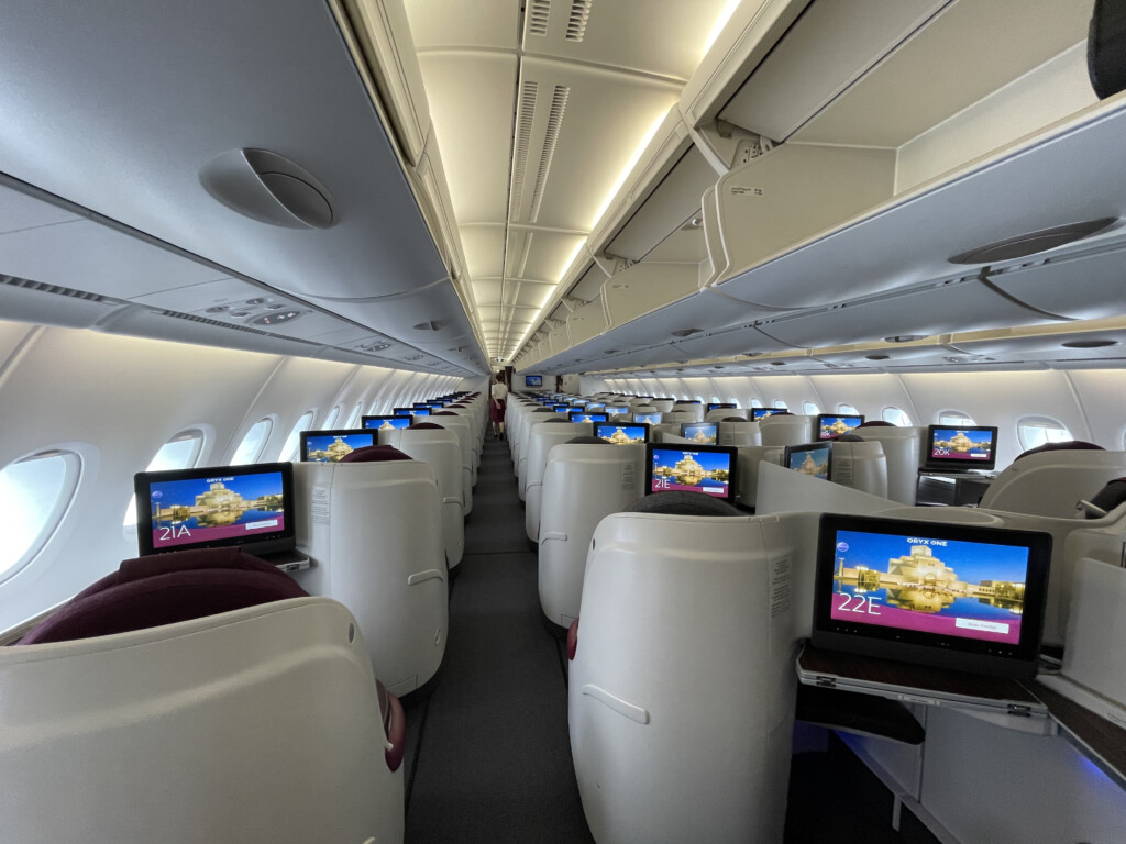 rows of seats with monitors on the side of the plane