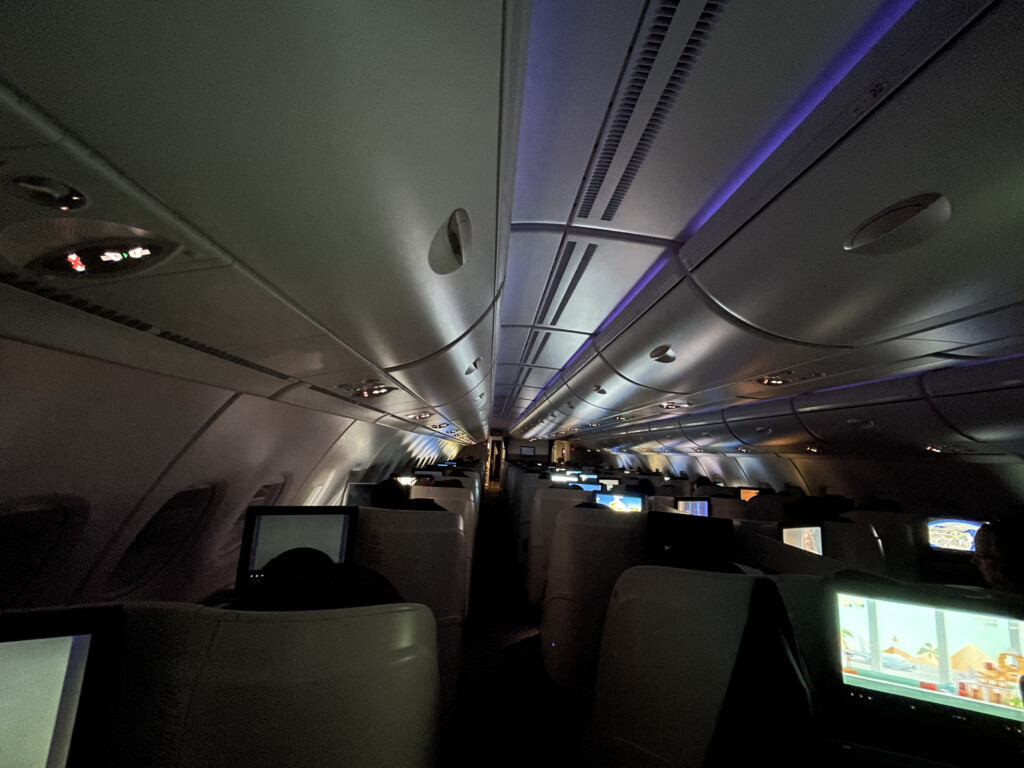 inside an airplane with rows of seats and monitors