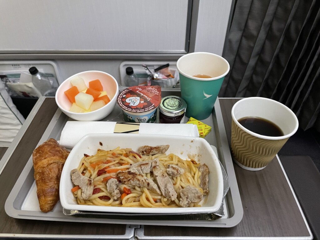 food on a tray with a croissant and a cup of coffee