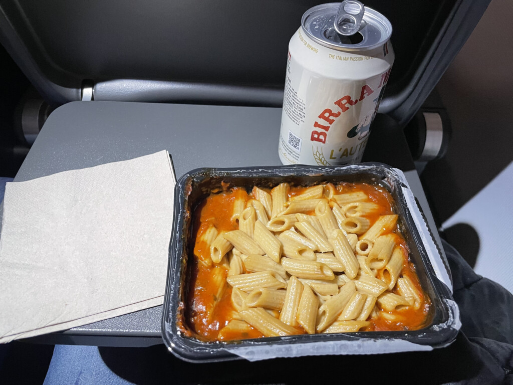 a tray of pasta and a can of beer