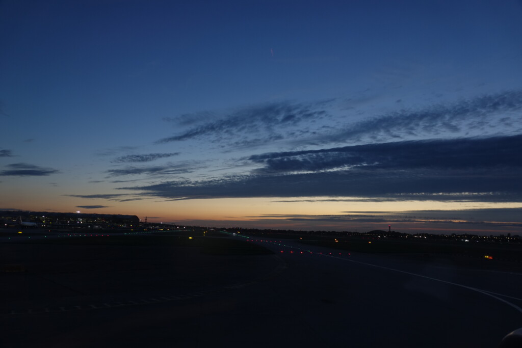 a runway at dusk with a blue sky and clouds
