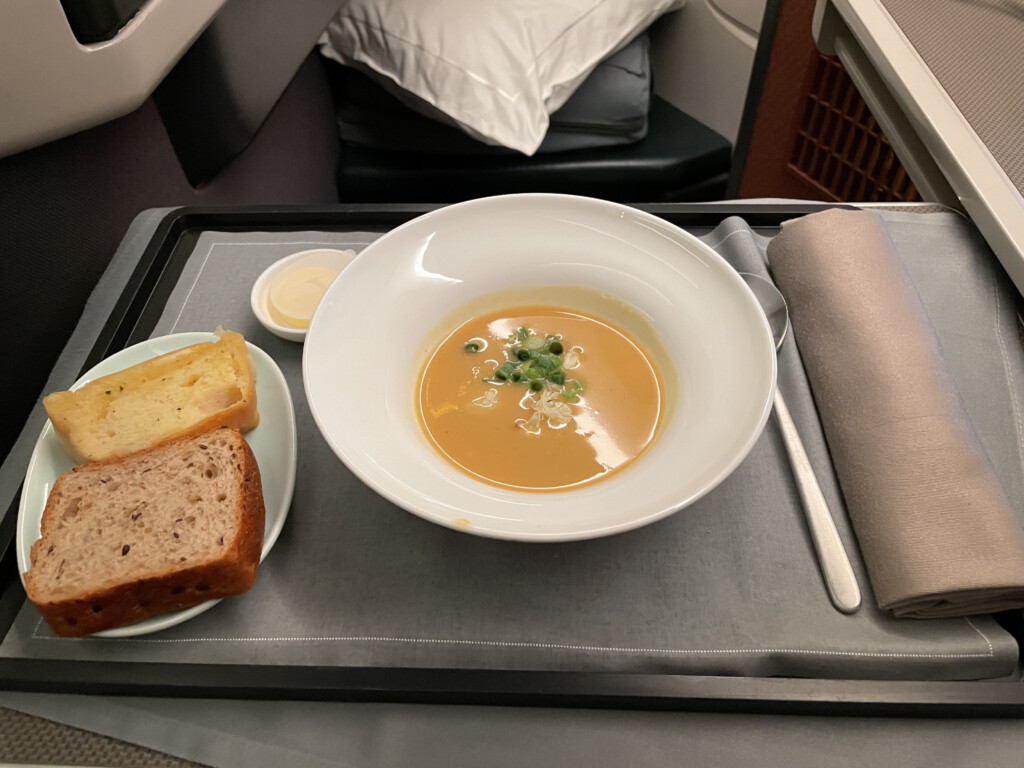 a bowl of soup and bread on a tray