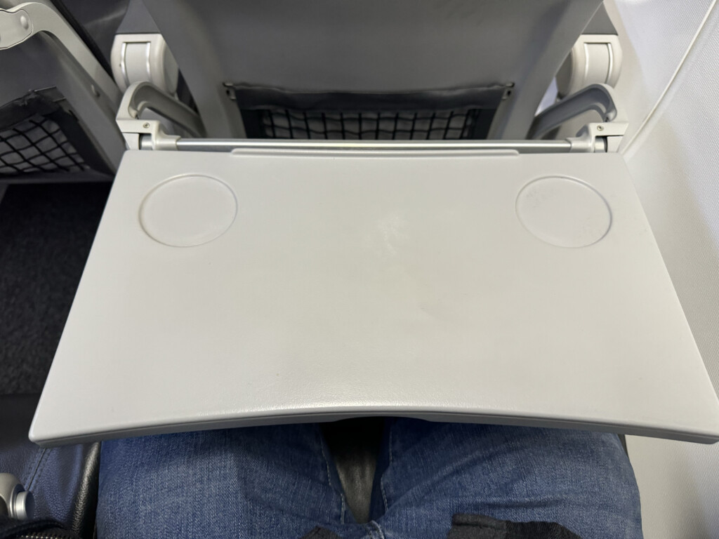 a person's legs in a seat with a grey rectangular object