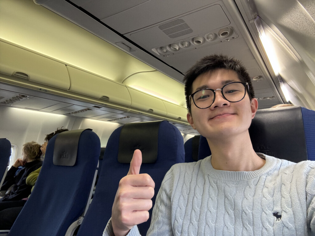 a man sitting in an airplane with his thumb up
