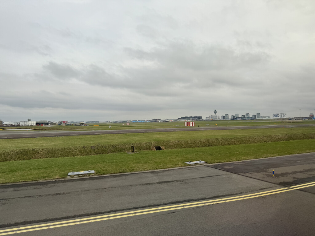 a runway with grass and buildings in the background