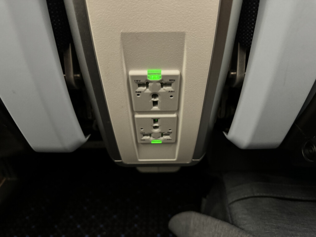 an airplane seat with a power outlet and green lights