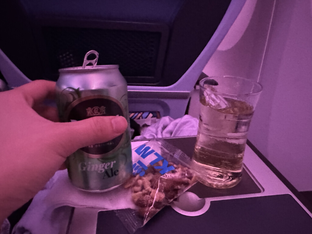 a hand holding a can of beer and a glass of liquid