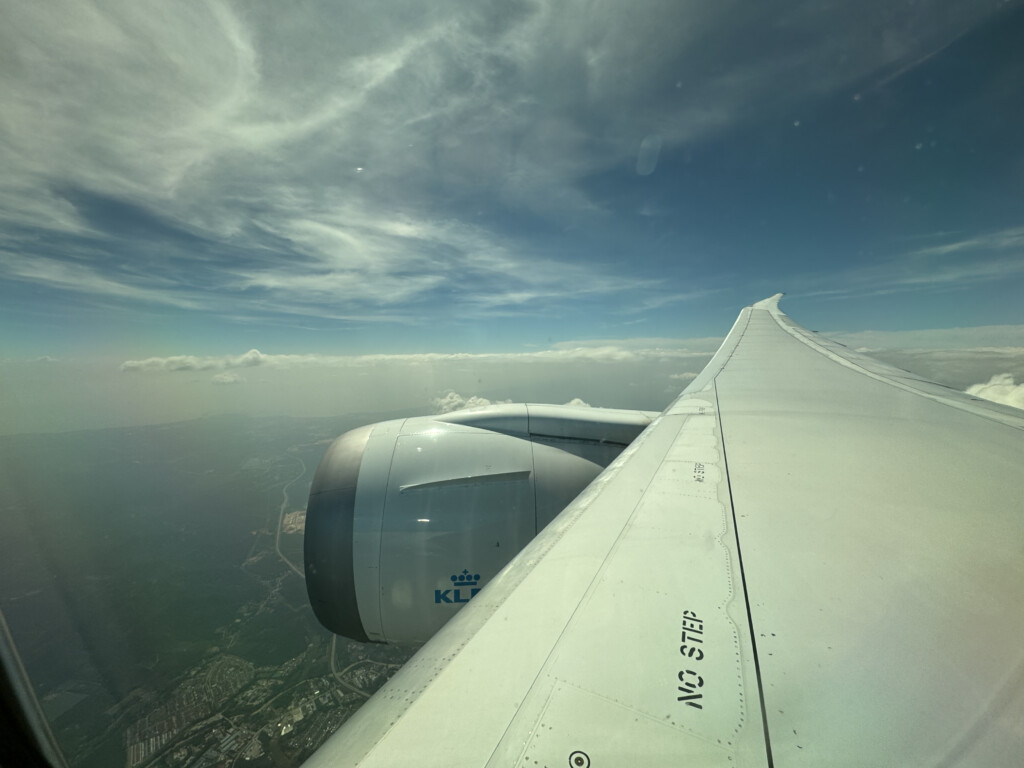 an airplane wing with a blue sky and clouds