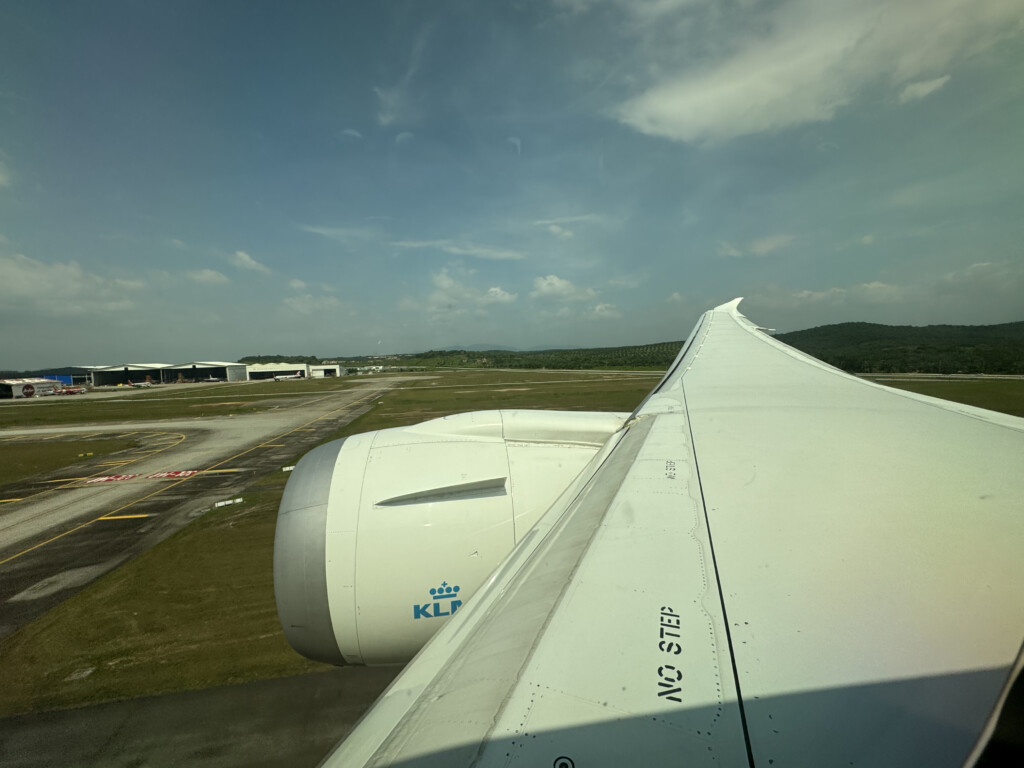 an airplane wing with a runway and buildings in the background