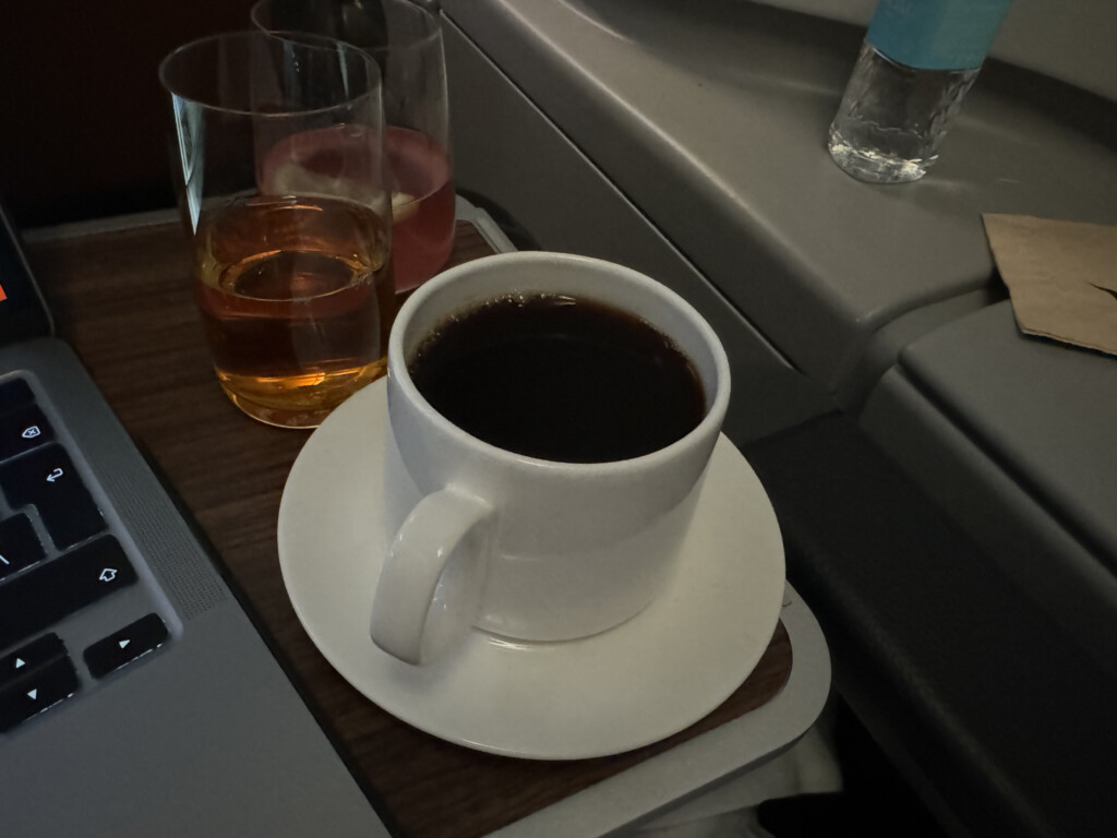 a cup of coffee and two glasses of liquid on a tray