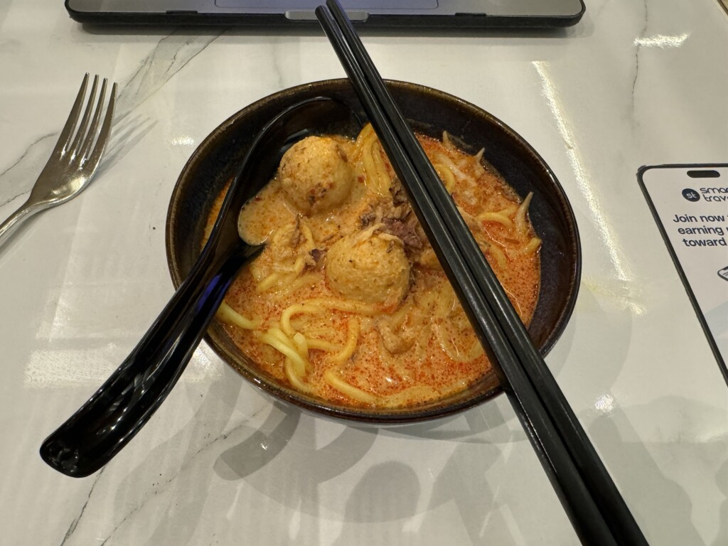 a bowl of soup with chopsticks and a fork